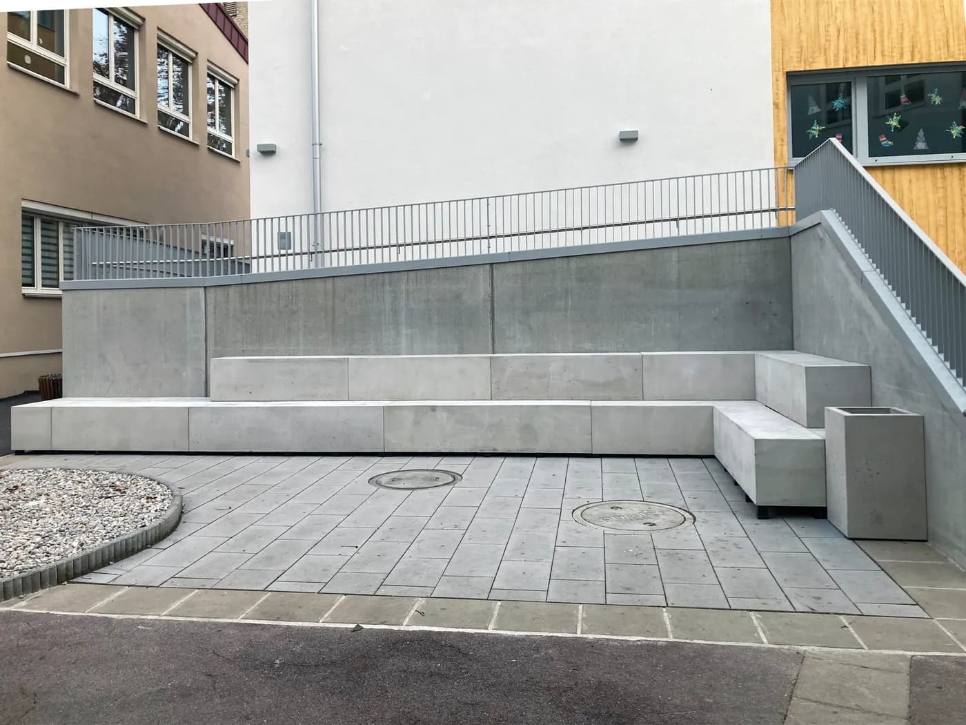 Maßgefertigte Betonbänke und ein Pflanzgefäß in einer Außenanlage